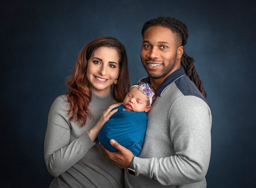 newborn photos what to wear newborn photoshoot biracial parents smiling with their newborn daughter