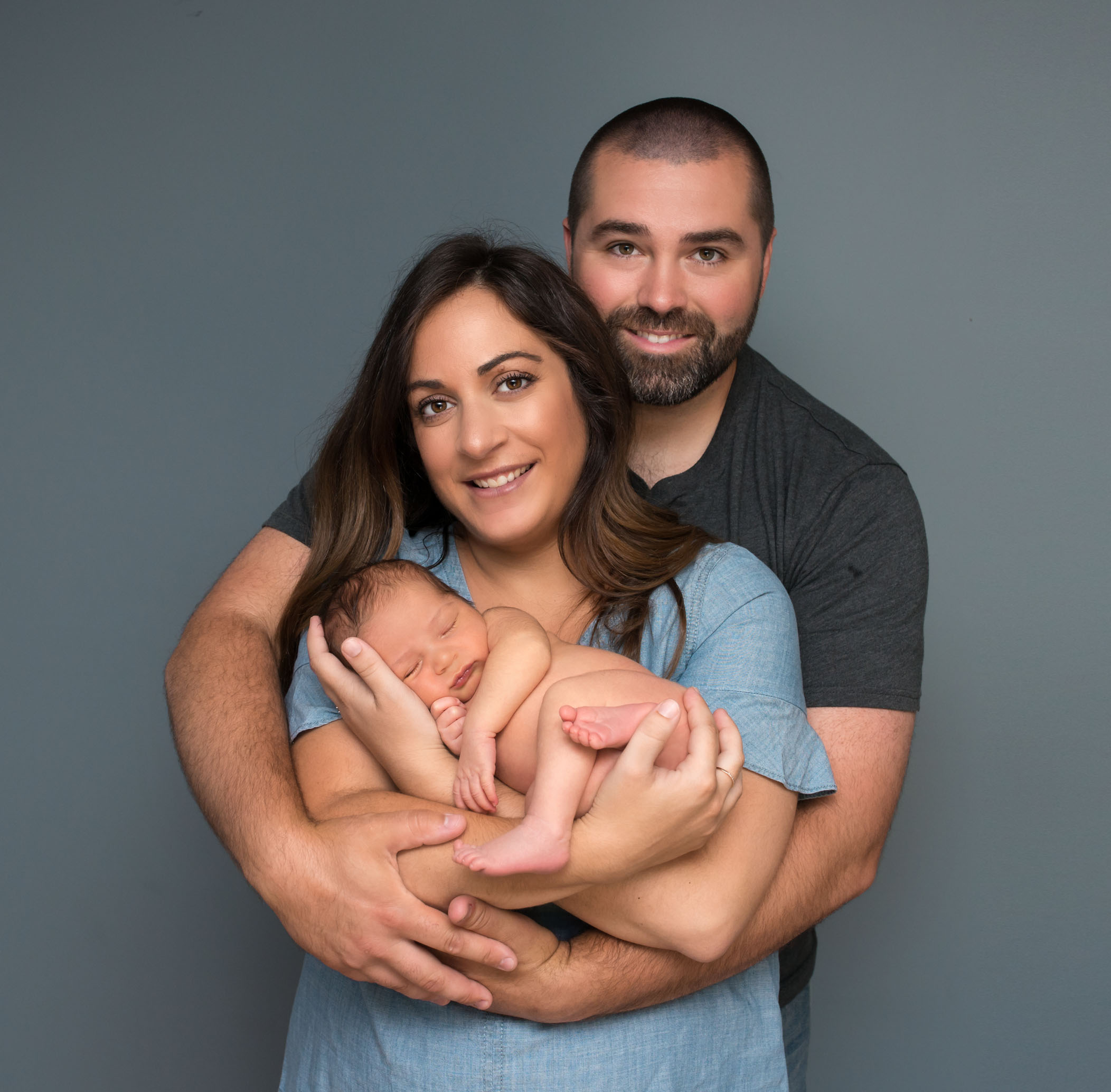 Mom and Dad cradle newborn son in their circle of arms