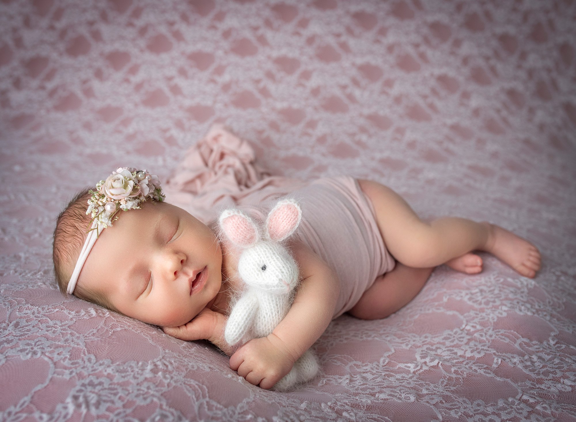 posed newborn photography baby lying on her side holding a knitted bunny