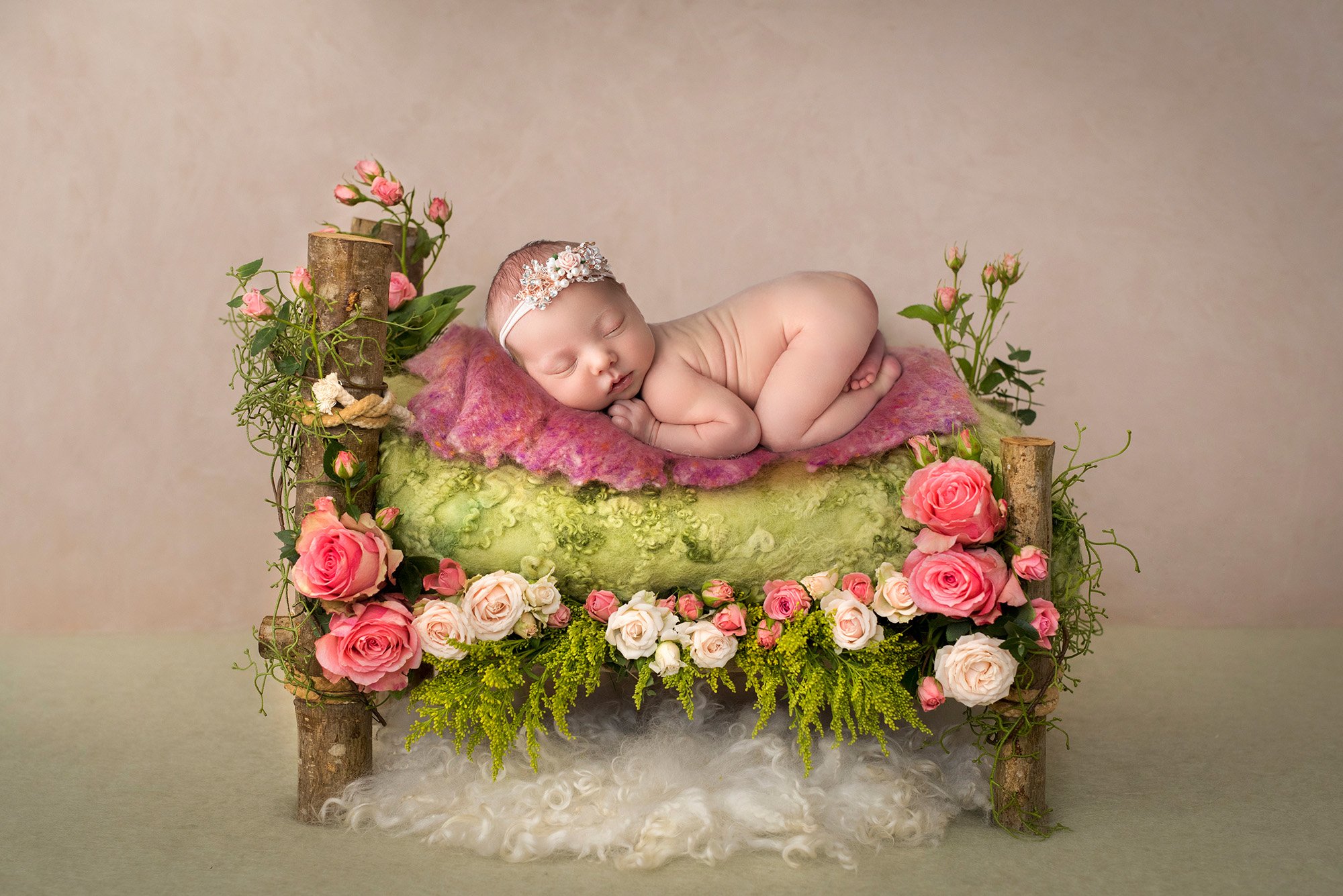 posed newborn photography baby girl sleeping on a woodland bed decorated in pink and white roses