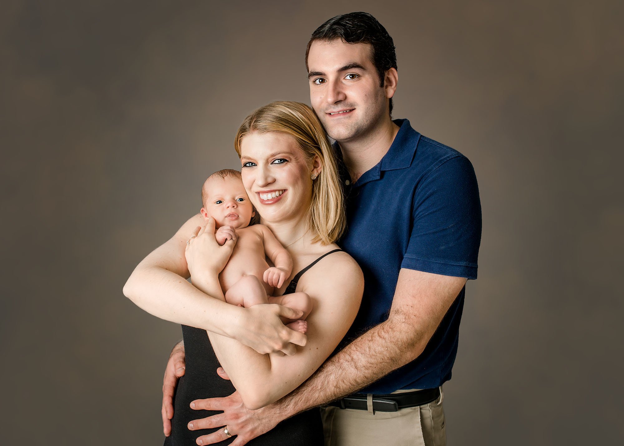 Family portrait with Dad, Mom and newborn baby on studio backdrop