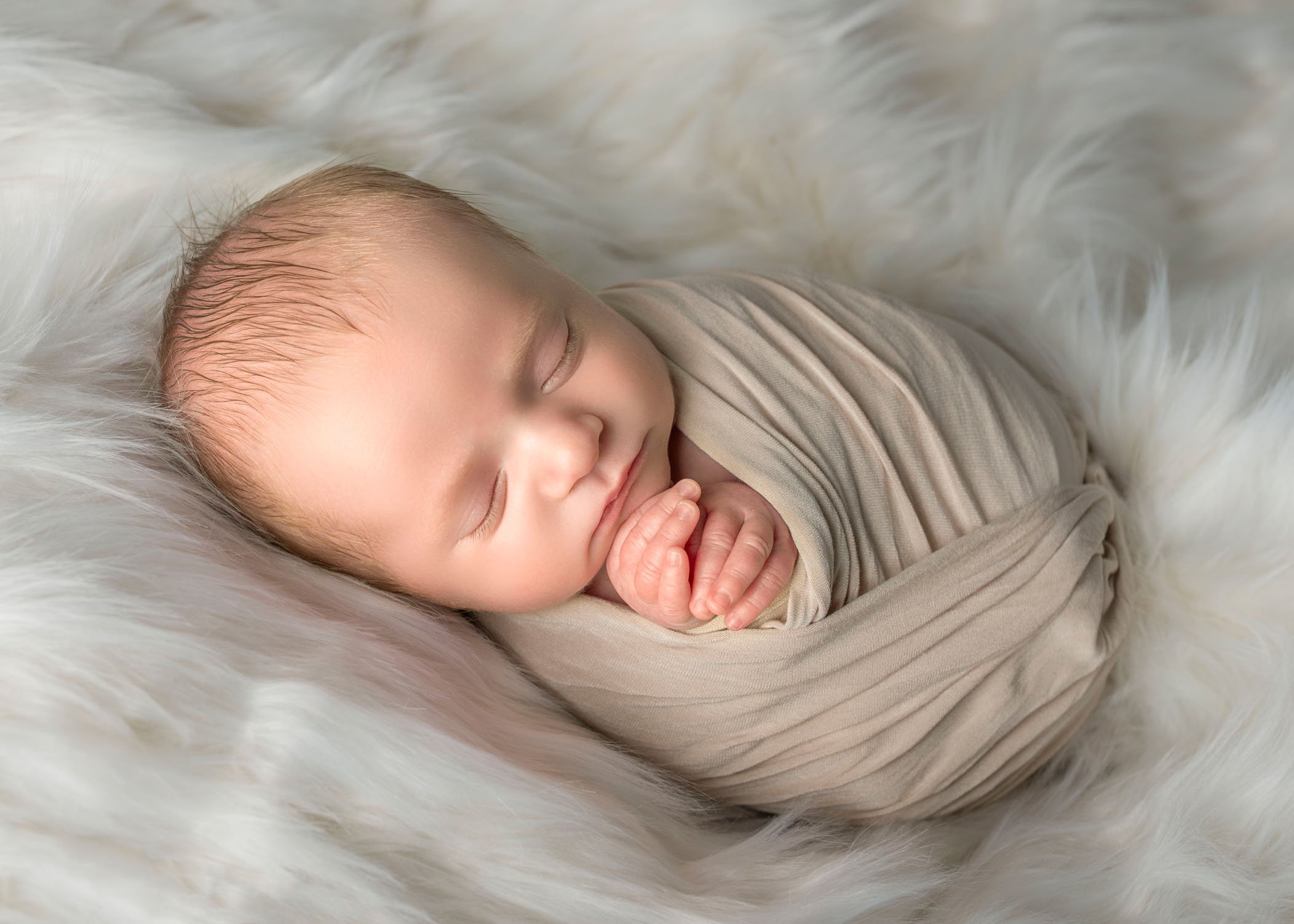 newborn boy wrapped sleeping on white fur
