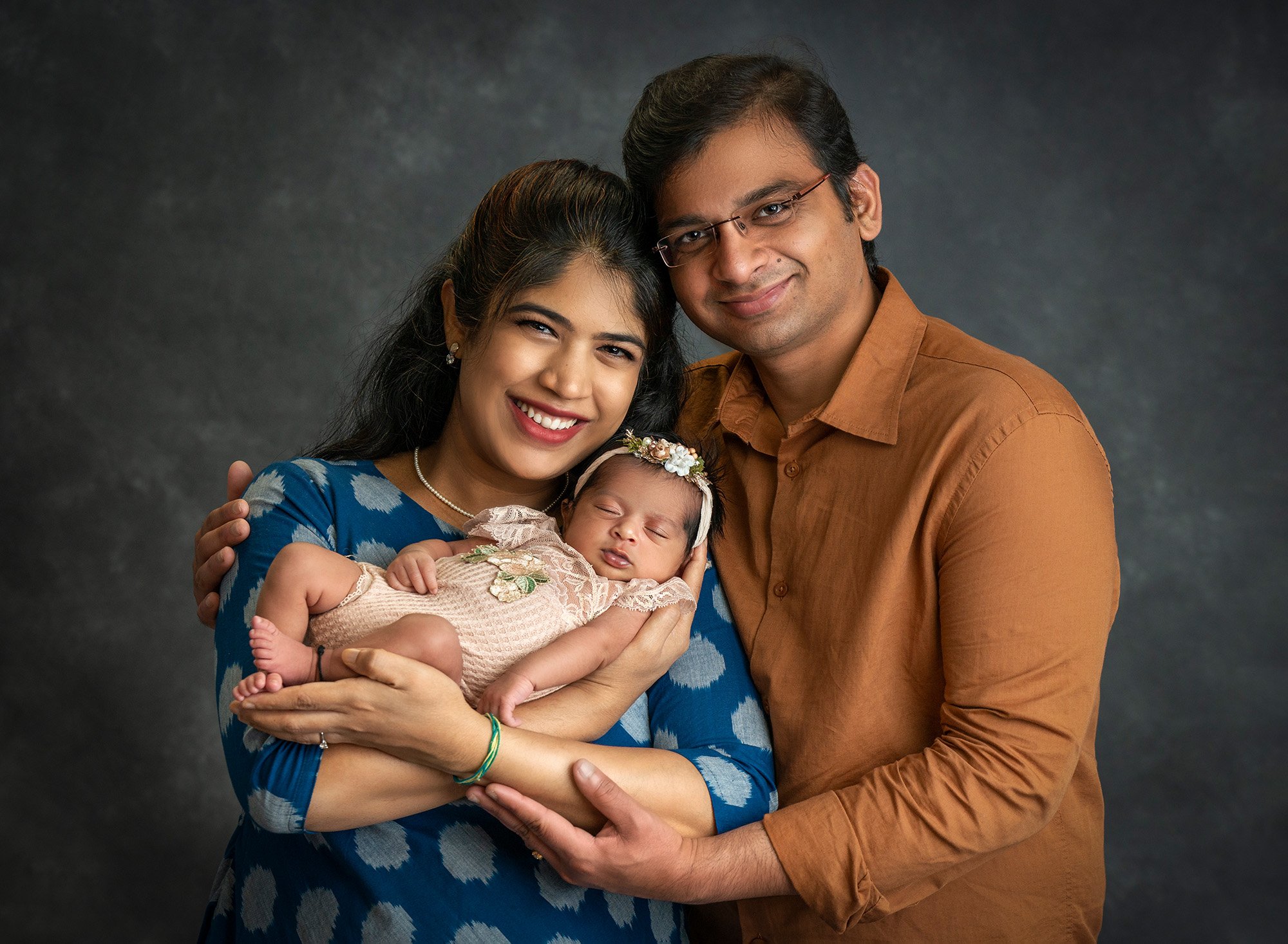 couple posing cradling newborn baby girl