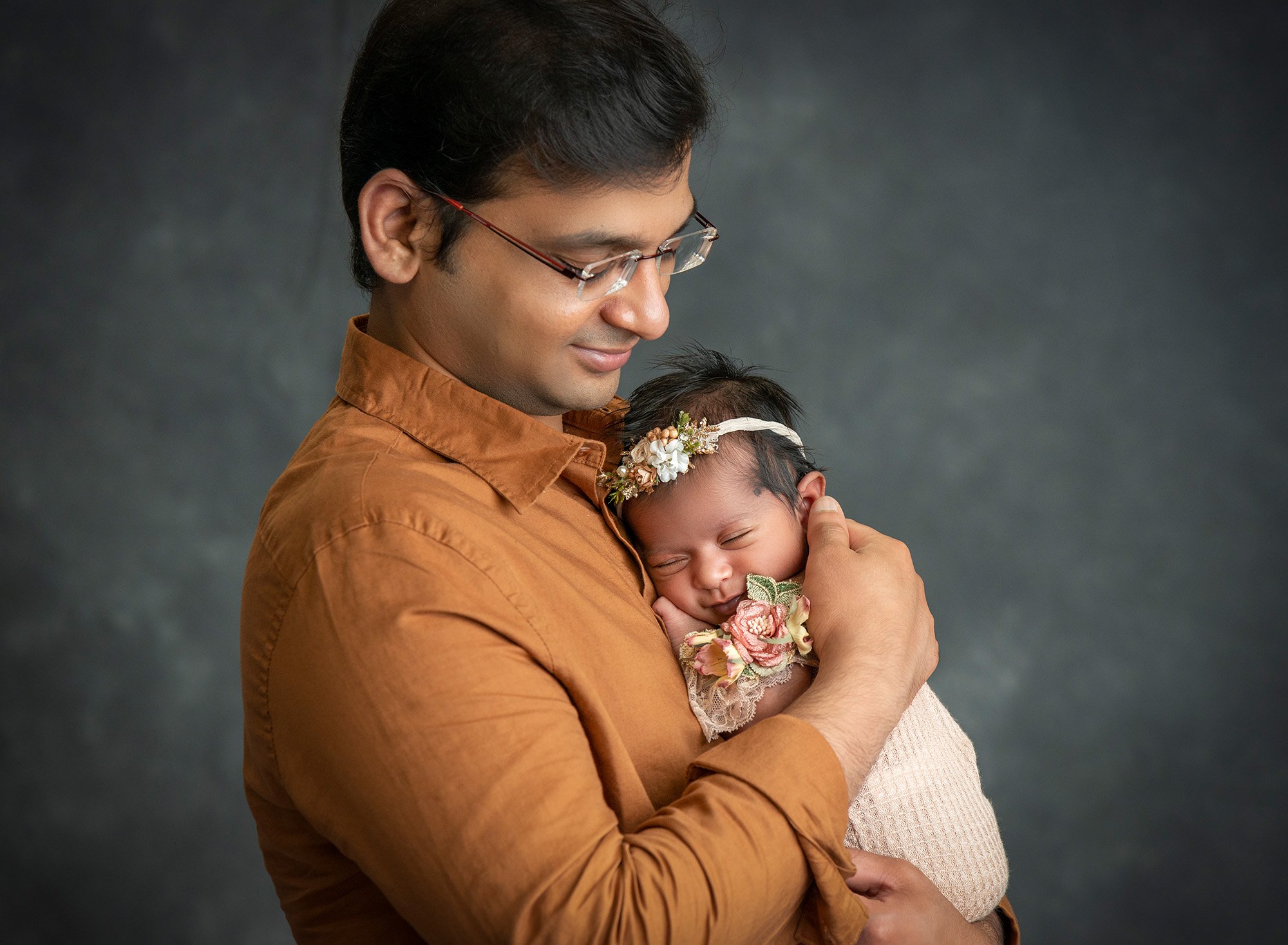 new father cradling newborn baby girl close to his chest
