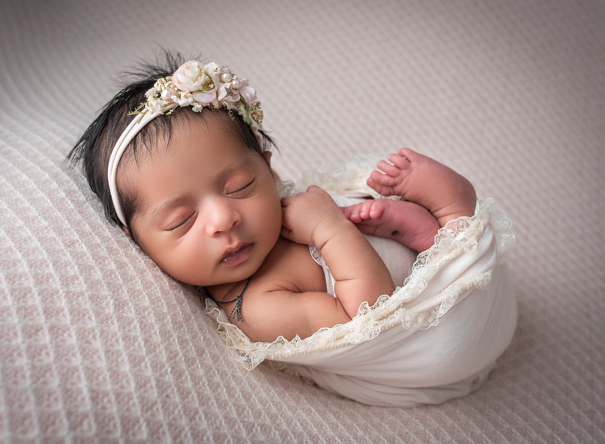 brunette newborn baby girl swaddled in lace